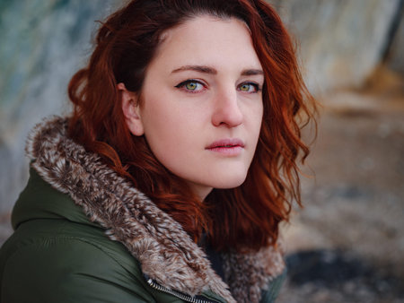 a redheaded woman walking along a mountain road in early spring. Hiker lady on nature landscape hikeの写真素材