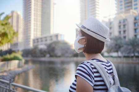 Summer sunny lifestyle fashion portrait of young stylish hipster Asia woman walking on the street, wearing cute trendy outfit and protective mask on faceの写真素材