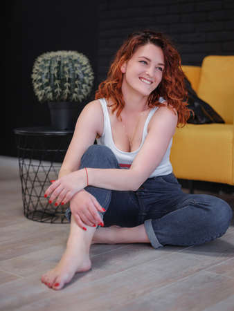 Studio portrait of romantic redhead young woman wearing jeans over dark wallの写真素材