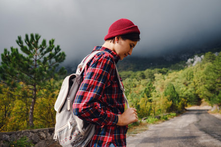 Happy young woman with backpack exploring misty mountains. Travel and wanderlust concept. Amazing...