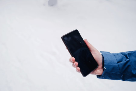 cell phone in a man's hand against a beautiful in the winter snow-covered forest .. winter seasonの写真素材