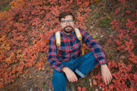 Male hipster Traveler with backpack in plaid shirt and jeans hiking in the mountains travel,...