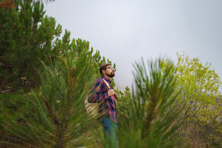 Male hipster Traveler with backpack in plaid shirt and jeans hiking in the mountains travel,...