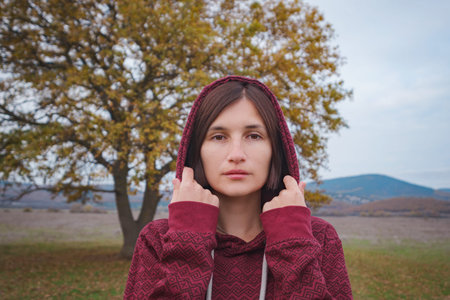 Portrait of a young asian woman in hoodie in the autumn nature. Outdoor atmospheric lifestyle portrait. Season and peopleの写真素材