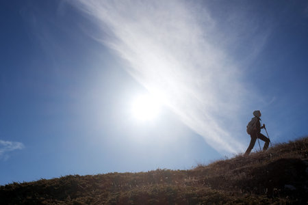 Young woman hiker with backpack on top of mountain on background of blue sky. Walk in the clouds....