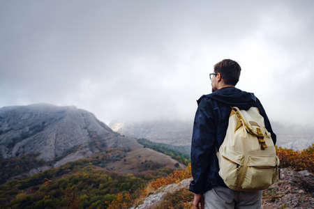 man with backpack and sticks for trekking hiking in the mountains. The beginning of autumn season. Beautiful foggy weatherの写真素材