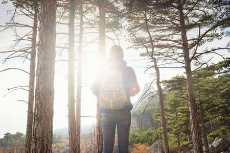 the concept of discovery and hiking, nature and freedom. woman is hiking in mountain, with a backpack climbs to the top of the mountain against the background of sunset. Active retirement.の写真素材