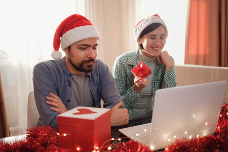 happy young couple use or watch something on laptop pc for christmas. video call celebrating virtual...