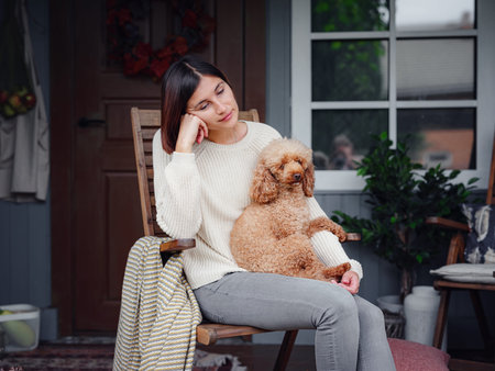 Young asian woman resting outdoors with cup of coffee on porch of country house, chilling outside with poodle dog. autumn lifestyle, leisure free time concept. Copy spaceの写真素材
