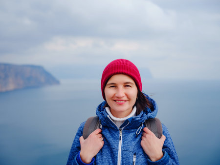Back view of woman in blue jacket and hat on shore of North sea on cold winter day. Mood...