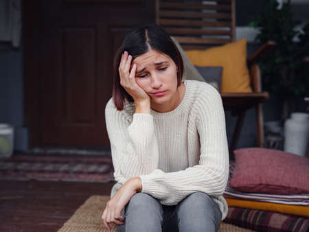 Young depressed asian woman sitting on porch of backyard. She feeling sad and worried suffering depression in mental health.の写真素材