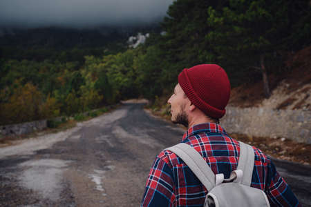 Man traveling with a backpack hiking in the mountains travel. Lifestyle success concept adventure, outdoor activities, plaid shirt hipster clothingの写真素材