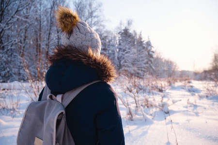 Happy Asian woman walking in winter snow forest. Cold weather hat and warm coat. idea and concept of healthy active lifestyle and good mood in any weatherの写真素材