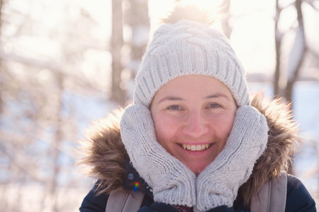 Happy Asian woman walking in winter snow forest. Cold weather hat and warm coat. idea and concept of...