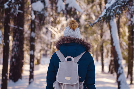 Happy Asian woman walking in winter snow forest. Cold weather hat and warm coat. idea and concept of healthy active lifestyle and good mood in any weatherの写真素材