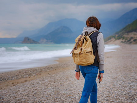antalya, turkey, winter walk by the mediterranean sea. Attractive young woman standing on a windy...