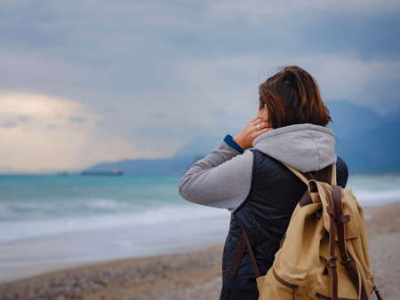 antalya, turkey, winter walk by the mediterranean sea. Attractive young woman standing on a windy cold beach.の写真素材