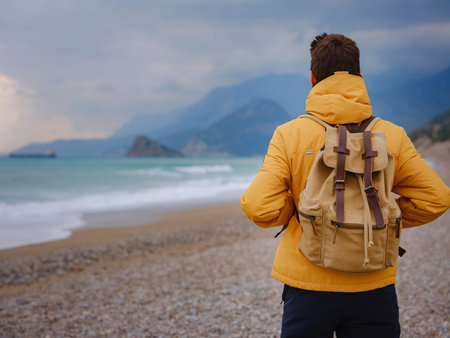 Handsome man in yellow jacket walking beach in antalya, turkey. Good looking male model looking...