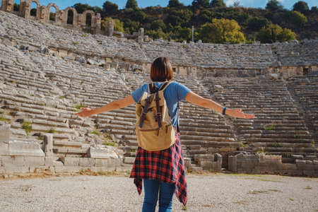 walk in Antalya Turkey on warm October afternoon. Pretty tourist woman with backpack at ruins of ancient city of Pergeの写真素材