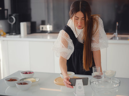 Young woman looks at a recipe for cooking a pie in a smartphone. food tutorial or cooking courses...