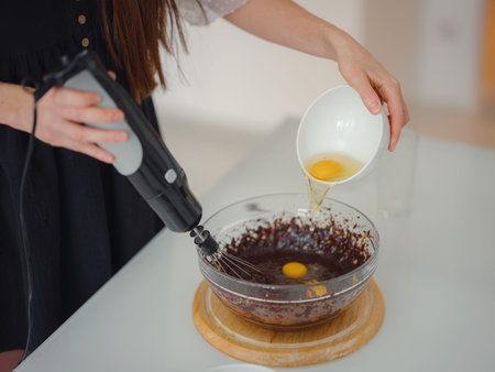 woman mix cocoa powder, sugar and flour to make dough with melted chocolate and walnuts for...