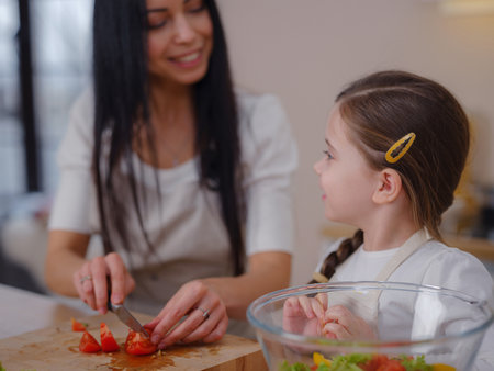 Happy mother and daughter enjoy prepare freshly salad together in kitchen. Healthy food at home. Healthy Lifestyle and Eating Concept. little influencer filming blog about healthy eatingの写真素材