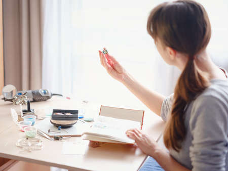 Lifestyle concept, work from home to reinvent your life - Jewelry designer workplace. Woman make jewelry. Georgian minankari enamel manufacturing technique. Jeweler making accessories in workshop.の写真素材