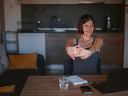 Asian creative female freelancer holding hands behind and close eye in front of laptop on desk. young woman relax from hard work in home office. smiling enjoy break stretching.の写真素材