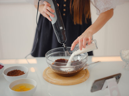 woman mix cocoa powder, sugar and flour to make dough with melted chocolate and walnuts for...