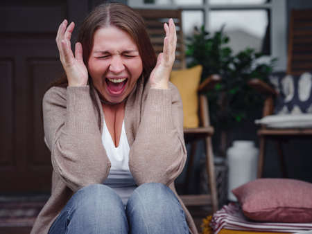 middle aged depressed woman sitting on porch. She feeling sad and worried suffering from depression in mental health. Problems and broken heart concept. Negative human emotion with cry of painの写真素材