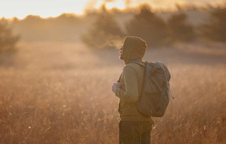 Young handsome man posing in autumn nature. guy standing in the field over sunset. Goals, hopes and...