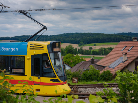 Basel, Switzerland - July 7 2022: public transport in the city. Yellow BLT tram waitind at tram station named Rodersdorf at City of Basel on a cloudy summer day.のeditorial素材