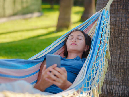young beautiful lady posing while lying on hammock, beautiful asian woman, brunette resting on vacation, relax, outdoor portrait. long weekend and vacation holidays spent slow life in Turkeyの写真素材