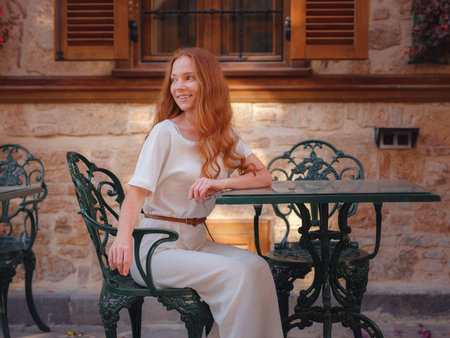 Happy woman tourist on background of blooming street. female traveler discover interesting places and popular attractions and sitting at table on terrace in old city Kalechi of Antalya, Turkey.の写真素材