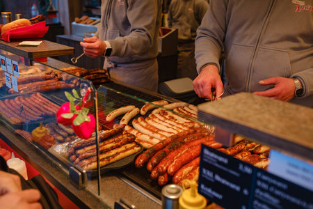 Dusselldorf, Germany - December 13, 2022: Bratwurst famous fried sausages, Grilling sausages on barbecue grill at food stall of Christmas market, winter wonderland.のeditorial素材