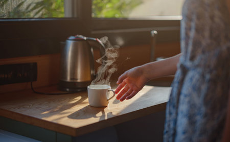 Woman is drinking coffee , morning routine. Tiny house. First property. Small apartment interior design. Minimalism. Moving in. Living alone. Charming trailer house with the morning sunの写真素材