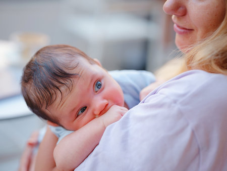 Diverse people portrait. Creative businesswoman balancing work and motherhood. Beautiful young mother working with laptop computer and breastfeeding, holding and nursing her newborn baby at cafe.の写真素材