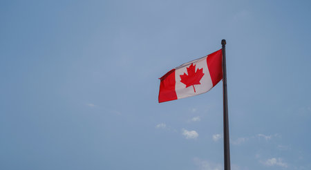 Flag of Canada flying against a blue sky.の写真素材