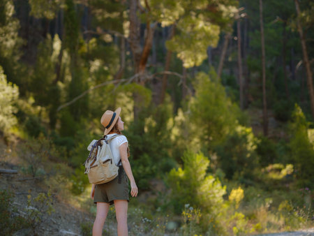 Caucasian ginger young beautiful female backpacker traveling alone in the forest. Attractive traveler look around and explore while walk in nature wood with happiness and fun during holiday vacation trip.の写真素材