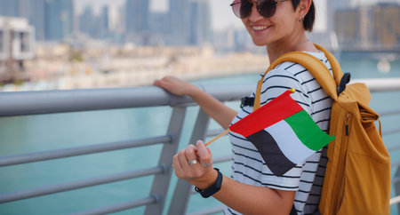 asian happy traveler woman with hat and yellow backpack with the flag of the United Arab Emirates...