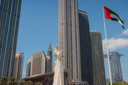 20 March 2023, Dubai, UAE: three fingers statue near UAE flag in sunny day and Burj Khalifa known as tallest skyscraper in world, United Arab Emirates. It is known for being worlds tallest building.のeditorial素材