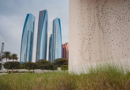 Abu Dhabi, UAE - March 19, 2023: Founders monument with the face portrait of Sheikh of United Arab Emirates and Etihad towers in Abu Dhabi. Modern architecture in arabian city.のeditorial素材