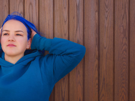 Female wearing light blue oversize hoodie and jeans. Blue haired woman outdoor at park near beach Antalya. Clothing mockup, Empty space for text o design.の写真素材