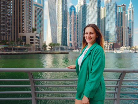 young woman in green suit walks streets of Dubai, Dubai Marina district. United Arab Emirates trip concept. the idea of successful expat, moving to another country, work visaの写真素材