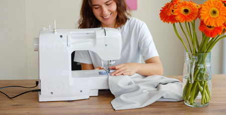 Fashion, fabric and sewing, woman at machine in small business with creative ideas and focus at home studio. Creativity, startup and design, tailor or designer stitching, young entrepreneur at work.の写真素材