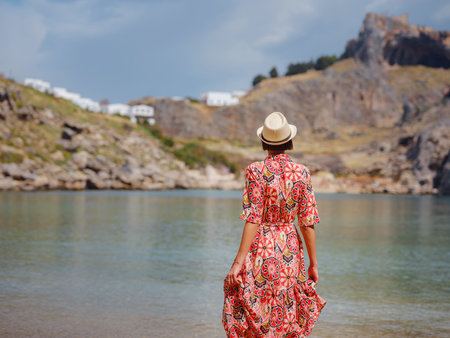 Nice Happy Female Enjoying Greek Islands. Travel to Greece, Mediterranean islands outside tourist season. Having fun at stunning views on sea resort and old town of Lindos on mountainの写真素材
