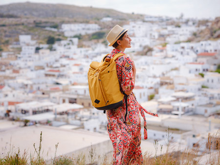Nice Happy Female Enjoying Greek Islands. Travel to Greece, Mediterranean islands outside tourist season. Having fun at stunning views on sea resort and old town of Lindos on mountainの写真素材
