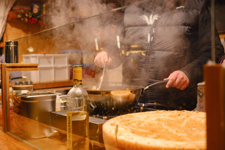 Dusselldorf, Germany - December 13, 2022: cooking delicious pasta with cheese at the fair Christmas market. food preparation at the festivalのeditorial素材
