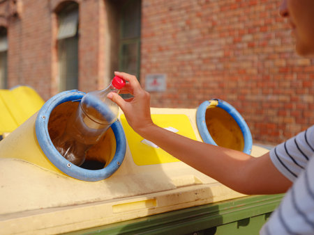 woman throwing plastic bottle Recycling bin stand on european street. Waste separation rubbish before drop to garbage bin to save world, environment care. Pollution trash recycling management conceptの写真素材