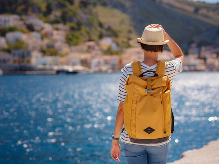 Nice asian Happy Female with backpack Enjoying her holidays on Symi Islands. View of port Symi or...
